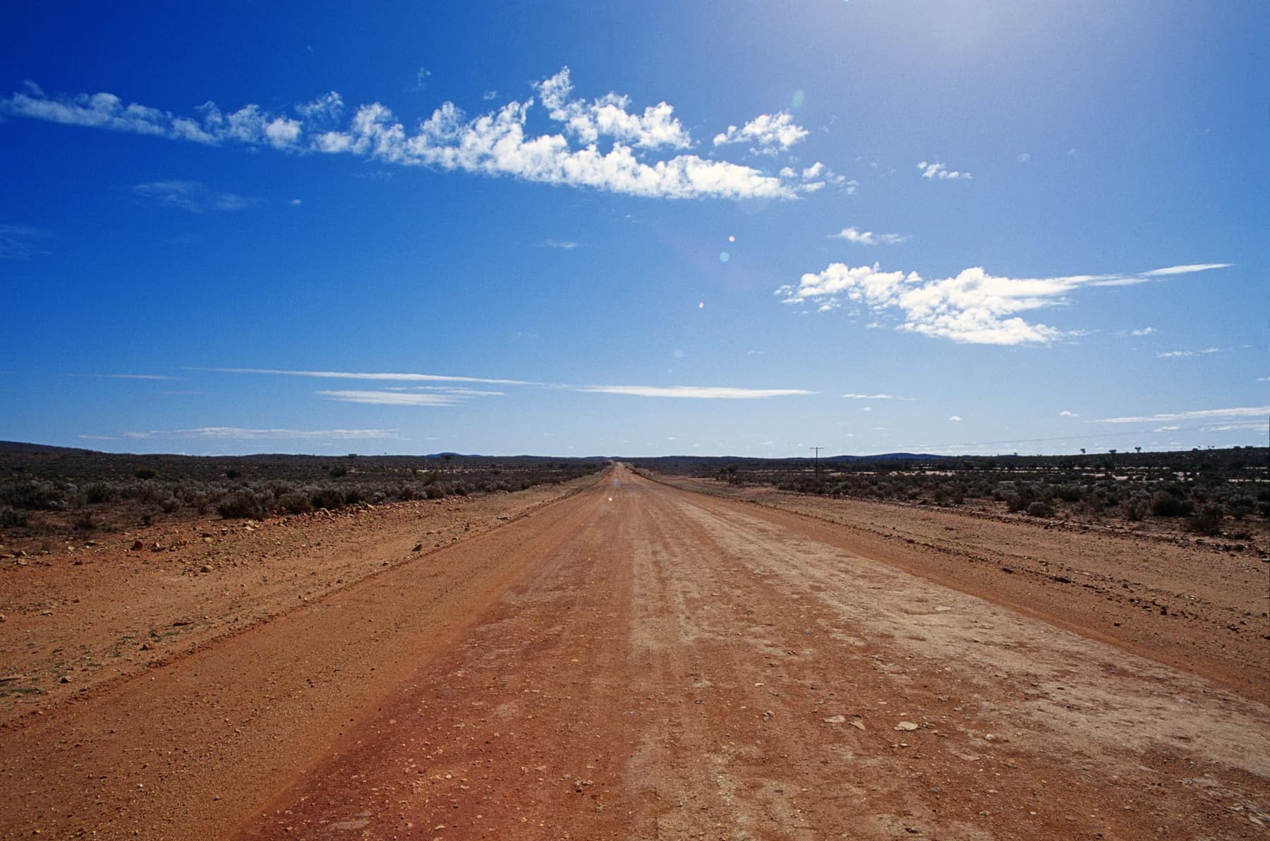 Unpaved road extending through a dry rural landscape